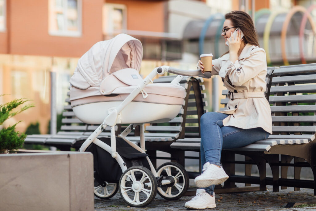 Une mère assise près de la poussette avec nacelle pour bébé