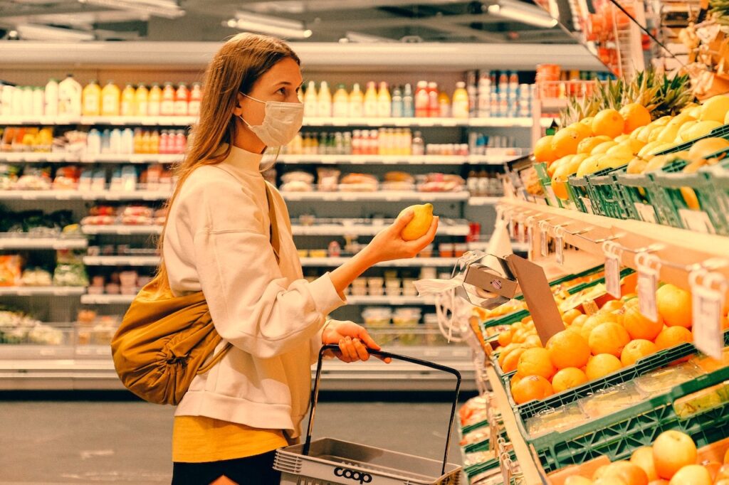 Femme regardant le rayon fruit au supermarché en tenant un citron dans la main